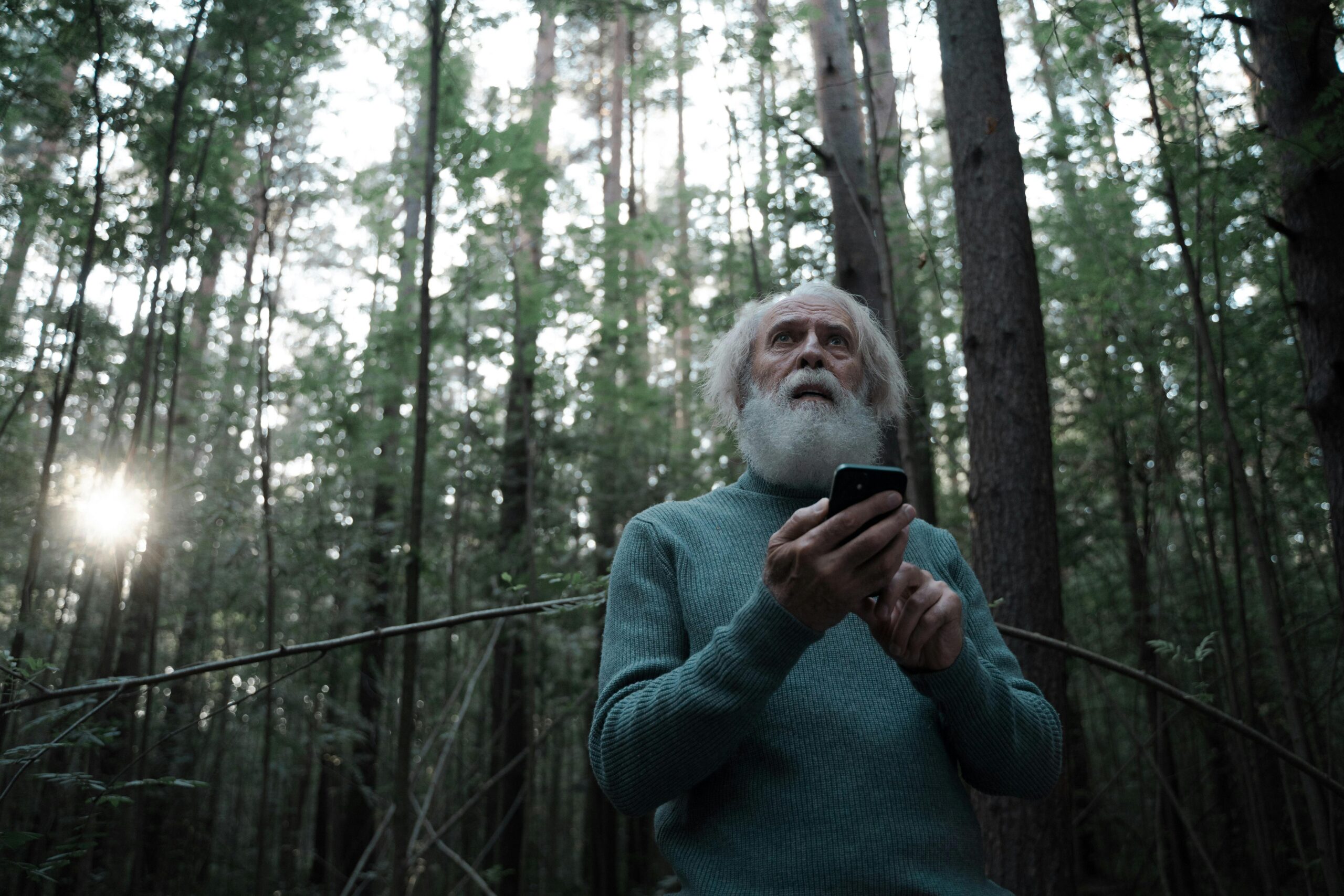 A white hair man with a mobile on his hands looking puzzled and worried