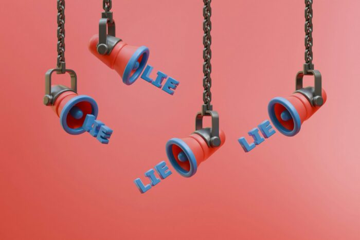 Speakers hanging from chains emitting the word lie