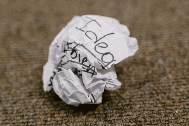 A crumpled up piece of paper with the word Idea on it.